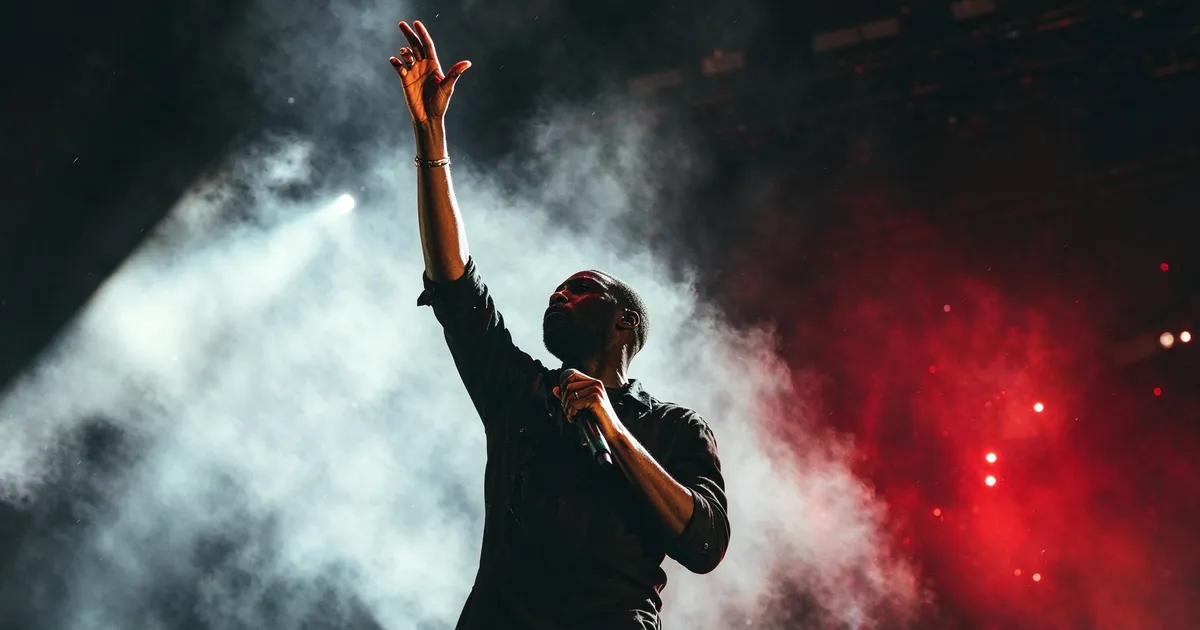 Singer raising an arm on a smoke-filled stage under red lights